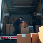 Movers calgary loading boxes into a truck with the Calgary skyline in the background.